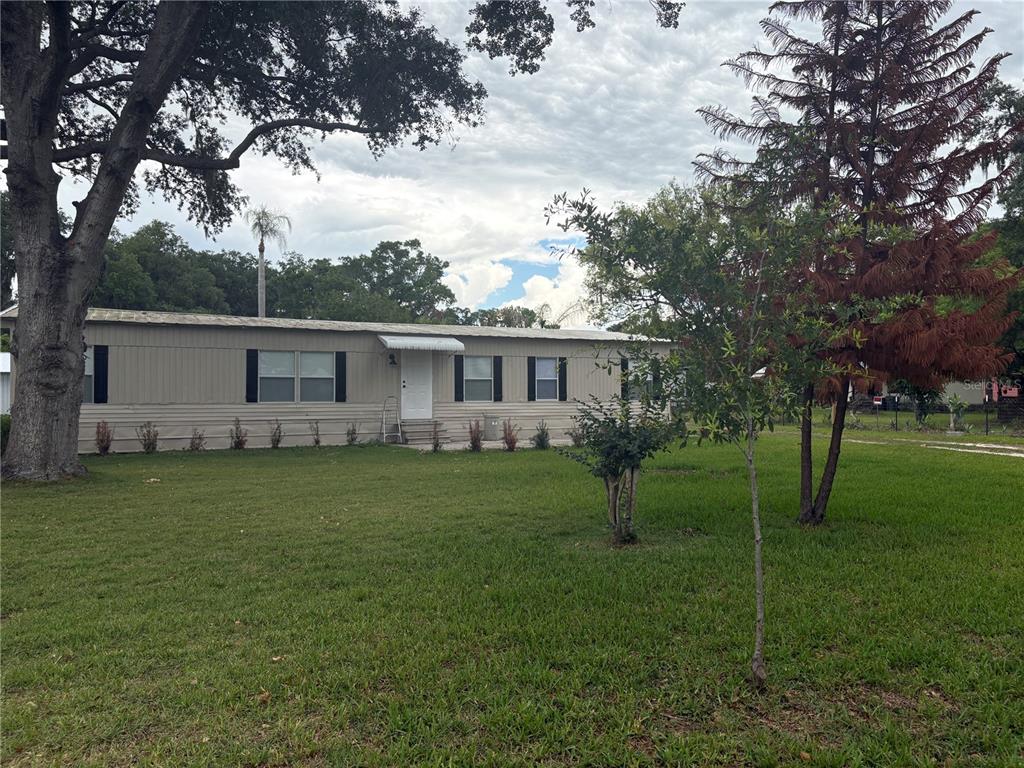 A single-story manufactured home with beige siding sits on a large, grassy lot — 3923 WARD ROAD, LAKELAND, FL
