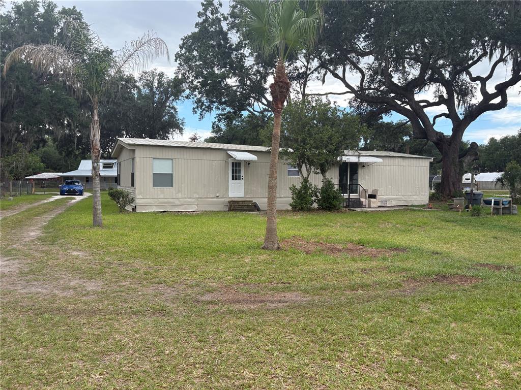 A single-story mobile home sits on a grassy lot with mature trees and a driveway — 3923 WARD ROAD, LAKELAND, FL
