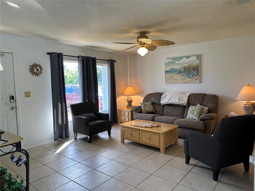 A living room features tile flooring, a brown sofa, two armchairs, and a ceiling fan — 18625 ALPHONSE CIRCLE, PORT CHARLOTTE, FL
