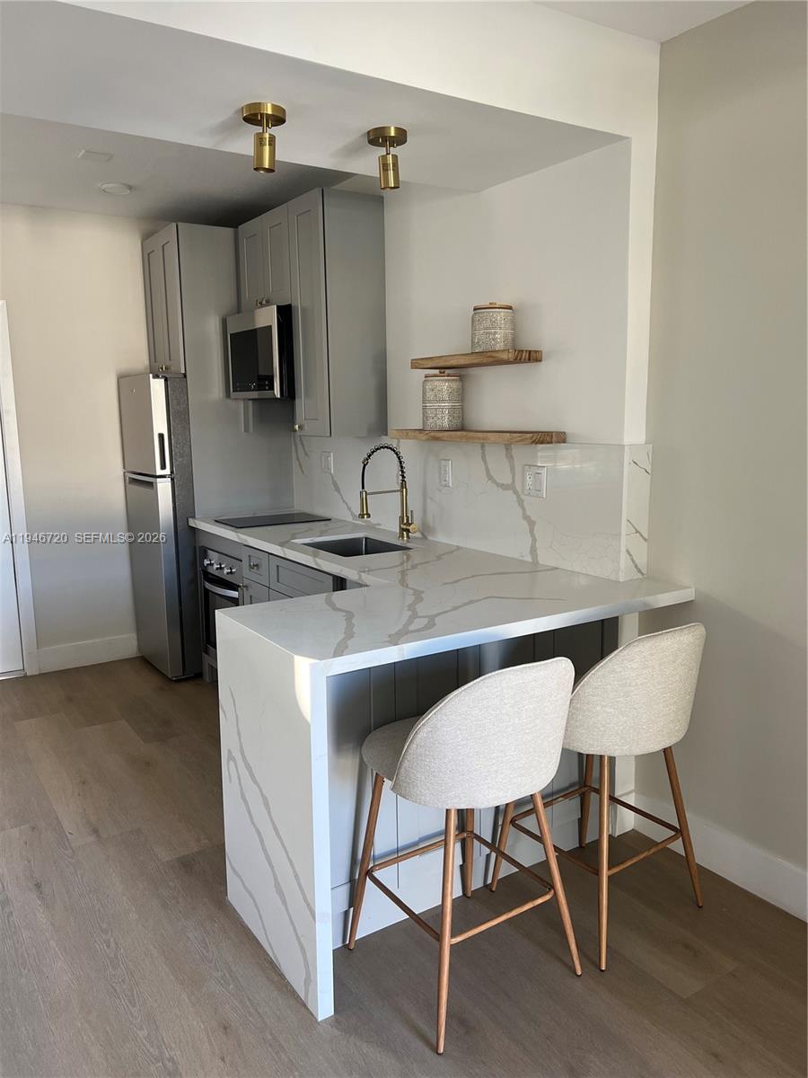 A modern kitchen features gray cabinets, white marble-patterned countertops, and two bar stools — 1129 NE 111th street # 1, Biscayne Park FL 33161, BISCAYNE PARK, FL