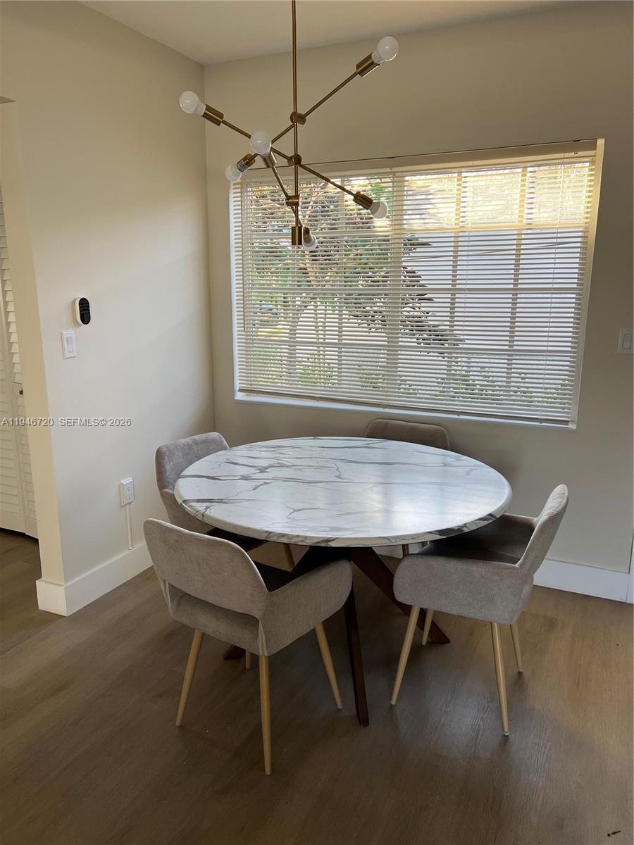 A dining area features a round marble-top table, four upholstered chairs, and a modern chandelier — 1129 NE 111th street # 1, Biscayne Park FL 33161, BISCAYNE PARK, FL