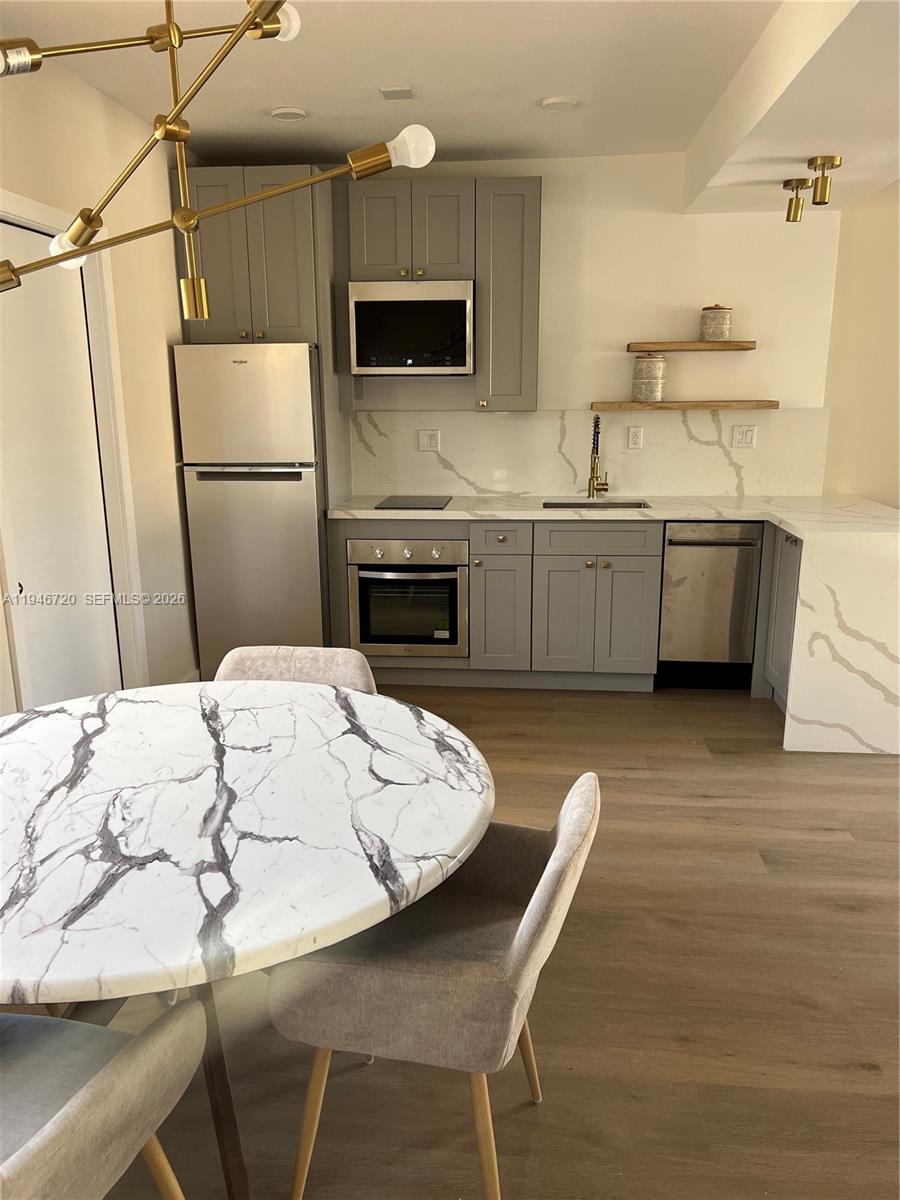 A modern kitchen features gray cabinets, white marble-patterned countertops, and a matching round dining table — 1129 NE 111th street # 1, Biscayne Park FL 33161, BISCAYNE PARK, FL