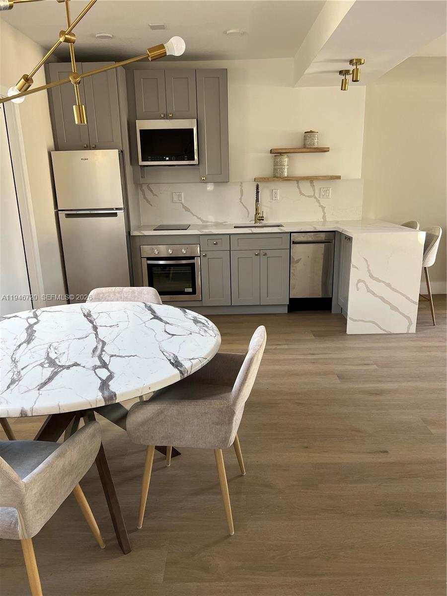 A kitchen features gray cabinets, white marble-patterned countertops, and a matching round dining table — 1129 NE 111th street # 1, Biscayne Park FL 33161, BISCAYNE PARK, FL