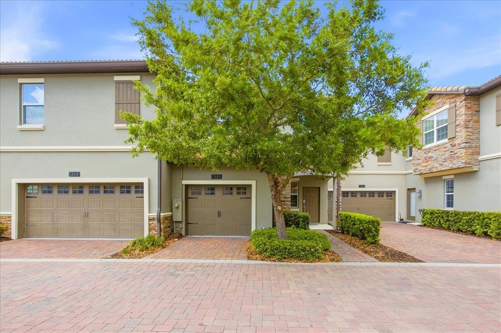 A multi-unit residential building features tan stucco walls, stone accents, and three garage doors — 1365 SHINNECOCK HILLS DRIVE, DAVENPORT, FL