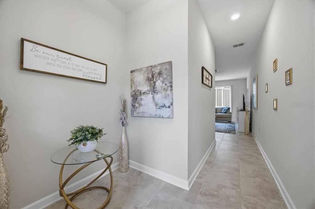 A tiled entryway leads into a hallway with wall art and a glass-topped accent table — 1365 SHINNECOCK HILLS DRIVE, DAVENPORT, FL
