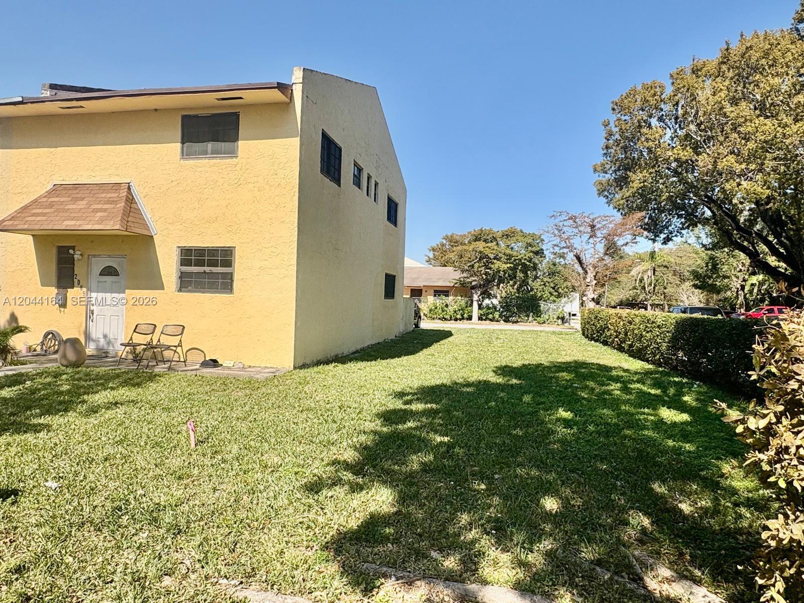 A yellow two-story building sits next to a large grassy lawn and a hedge — 2065 NE 139th St, North Miami Beach FL 33181, NORTH MIAMI BEACH, FL