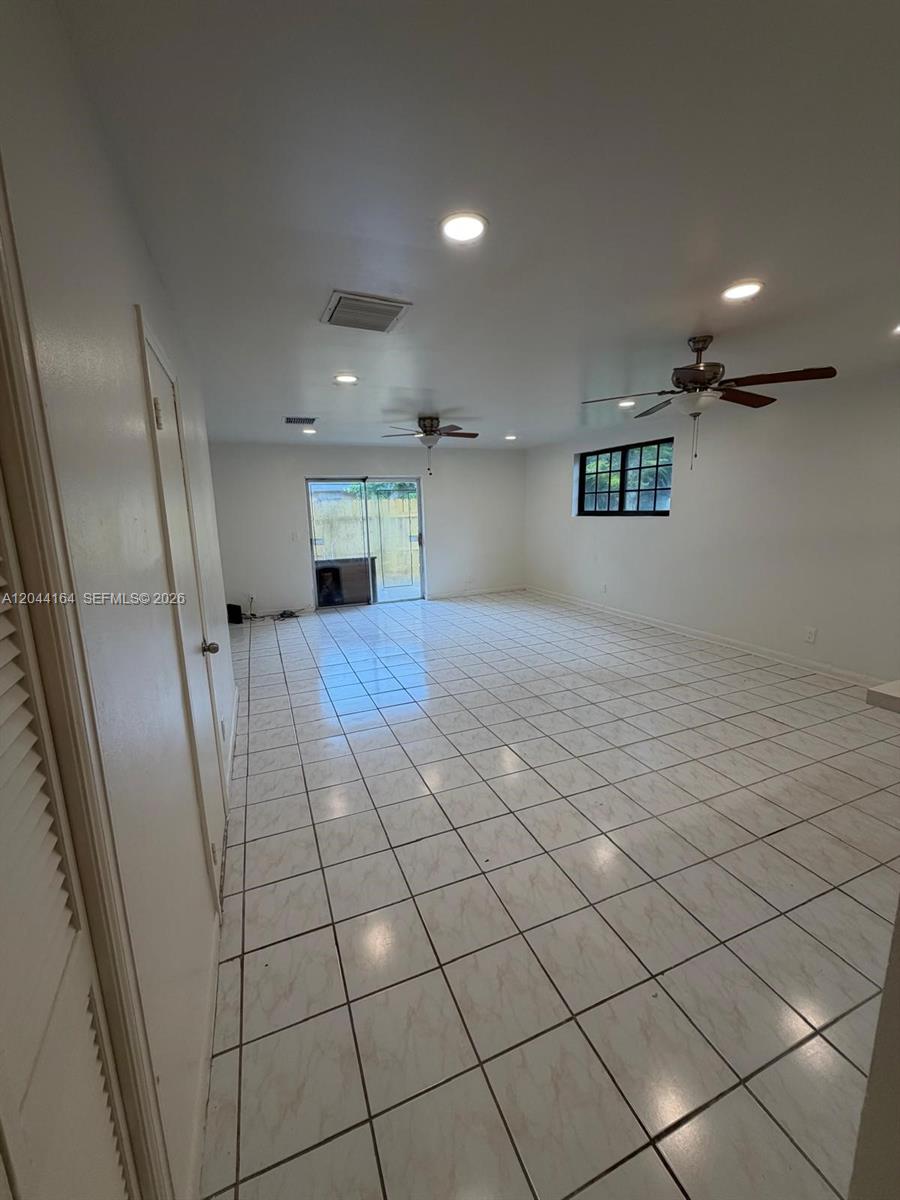 A spacious room features white tile flooring, recessed lighting, two ceiling fans, and sliding glass doors — 2065 NE 139th St, North Miami Beach FL 33181, NORTH MIAMI BEACH, FL
