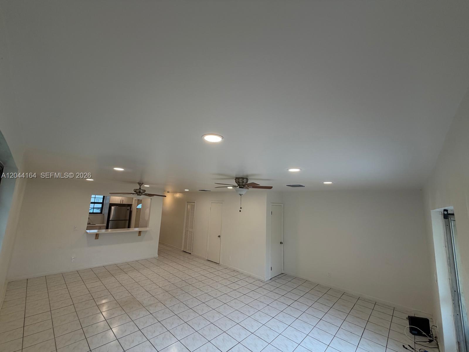 An open-concept living area features white tile flooring, recessed lighting, and a kitchen pass-through window — 2065 NE 139th St, North Miami Beach FL 33181, NORTH MIAMI BEACH, FL