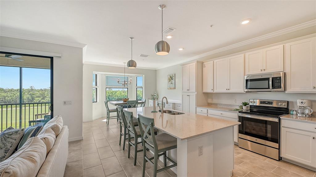 A kitchen with white cabinets, a quartz island, and a dining area overlooking a landscape — 17902 GAWTHROP DRIVE UNIT 402, LAKEWOOD RANCH, FL