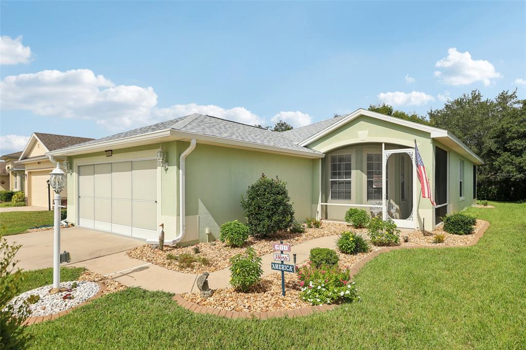 A light green single-story house with a two-car garage and a screened-in front porch — 4954 RAINBOW TROUT ROAD, TAVARES, FL