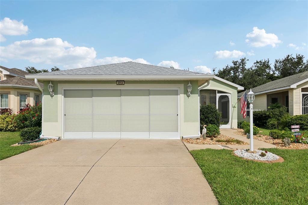 A single-story house with a light green exterior, a three-panel garage screen, and a driveway — 4954 RAINBOW TROUT ROAD, TAVARES, FL