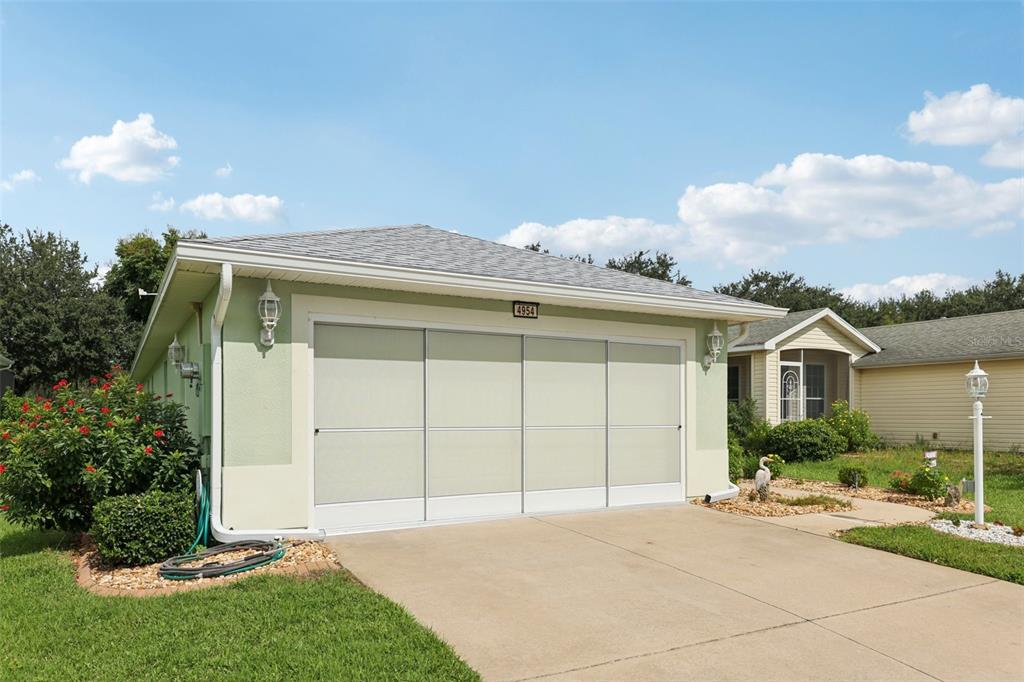 A light green garage with a sliding screen door and a concrete driveway — 4954 RAINBOW TROUT ROAD, TAVARES, FL