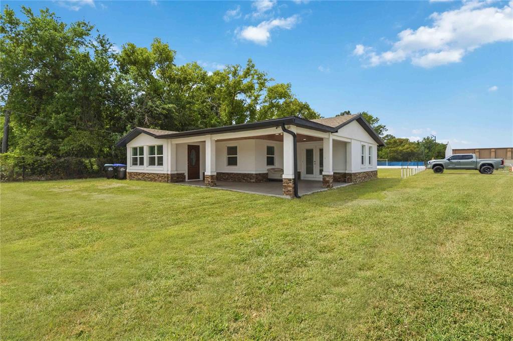 A single-story house with a covered porch, stone accents, and a large grassy yard — 4116 S GOLDENROD ROAD, ORLANDO, FL