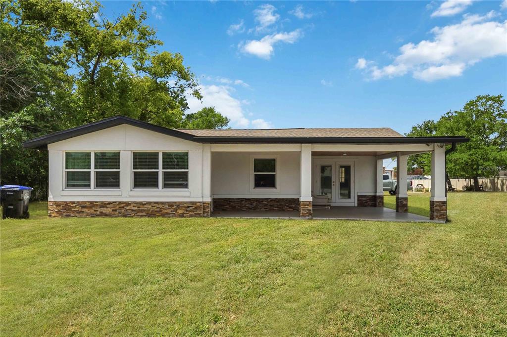 A single-story house with a covered patio, stone veneer base, and white exterior siding — 4116 S GOLDENROD ROAD, ORLANDO, FL