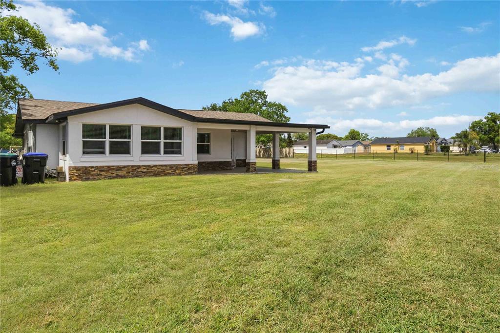 A single-story house with a stone-accented exterior and a covered patio overlooking a grassy yard — 4116 S GOLDENROD ROAD, ORLANDO, FL
