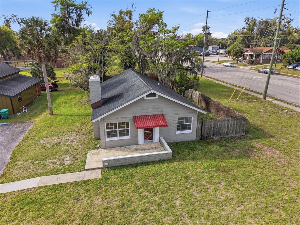 An aerial view shows a single-story gray house with a red awning and chimney — 1030 CAMPHOR LANE, DELAND, FL