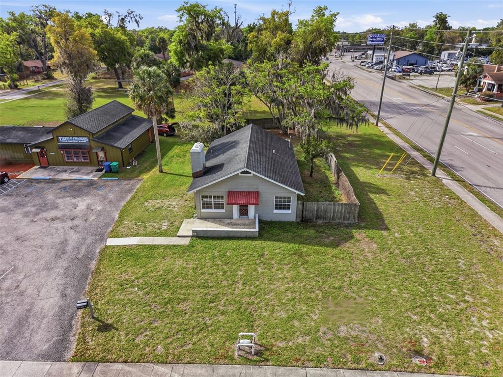 An aerial view shows a single-story house with a red awning next to a commercial building — 1030 CAMPHOR LANE, DELAND, FL