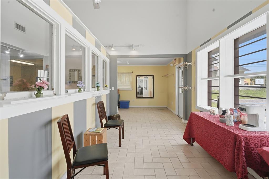 A bright room features yellow and gray striped walls, tiled floors, and large windows — 1030 CAMPHOR LANE, DELAND, FL