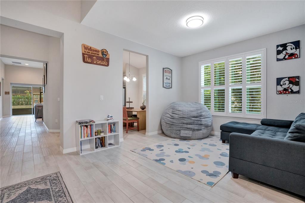 A living room features light wood-look flooring, a gray sectional sofa, a beanbag chair, and shutters — 1103 NATHAN RIDGE RD, CLERMONT, FL