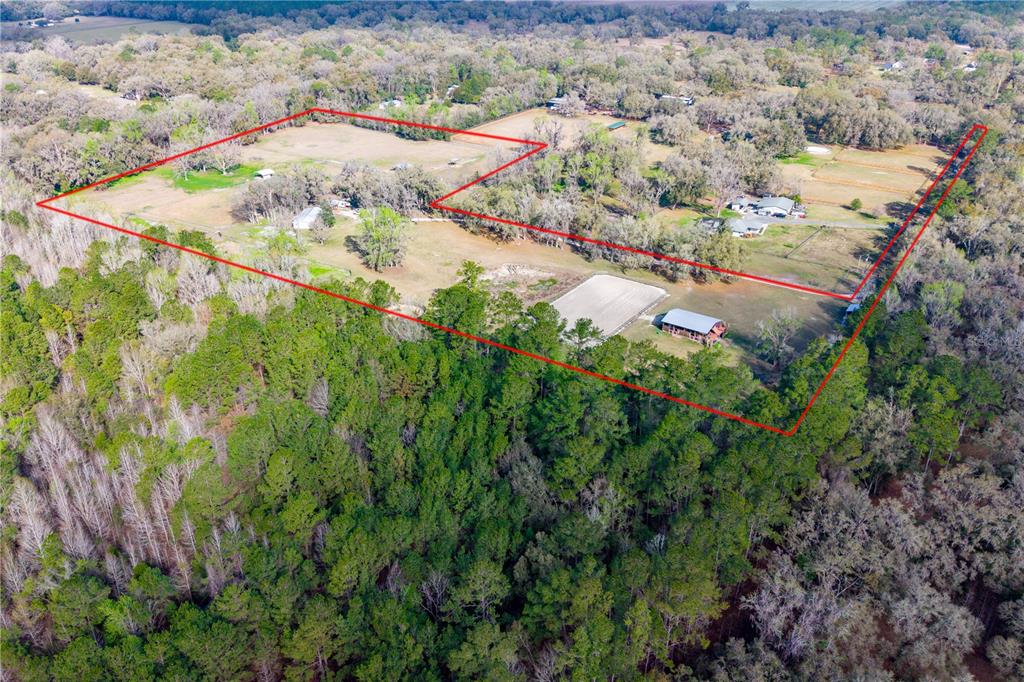 An aerial view shows a fenced rural property with a horse arena and barn — 16242 NW 130TH STREET, WILLISTON, FL