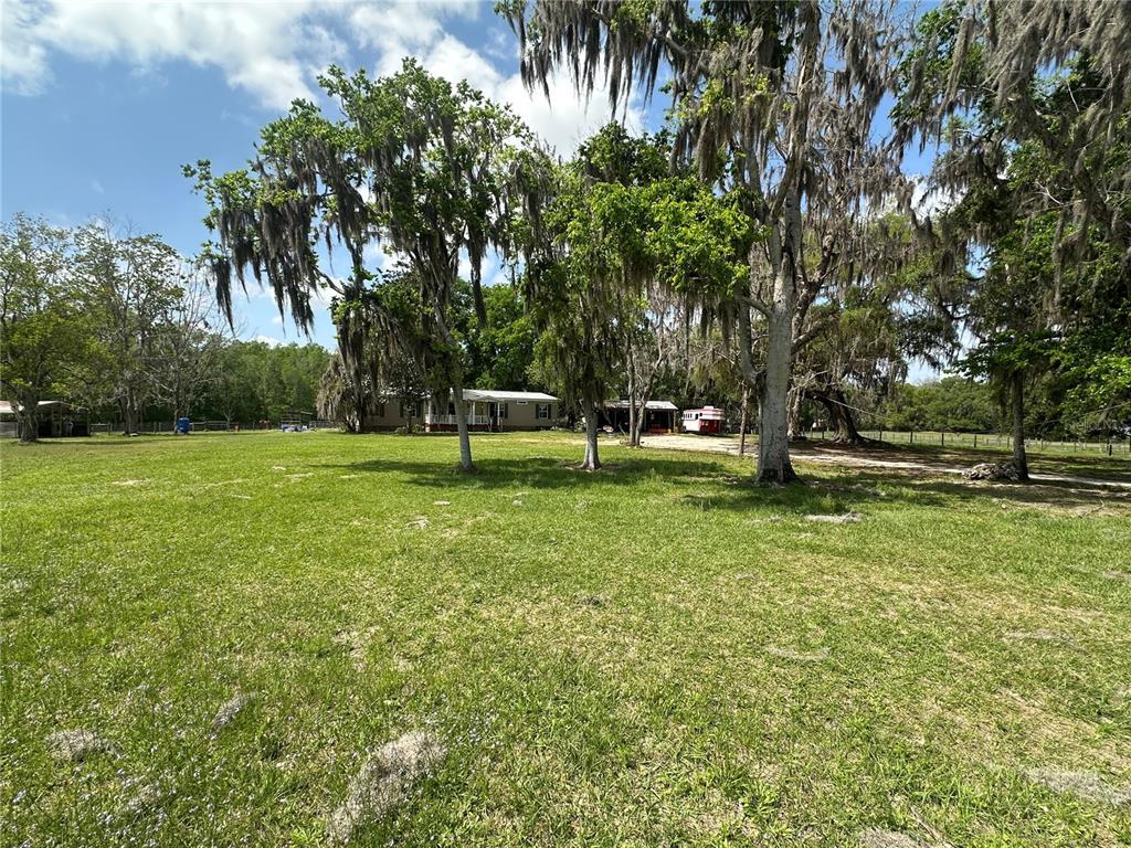 An aerial view shows a rural property with pastures, a barn, and an outdoor riding arena — 16242 NW 130TH STREET, WILLISTON, FL