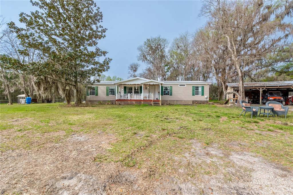 A grassy field leads to a house shaded by large trees with Spanish moss — 16242 NW 130TH STREET, WILLISTON, FL