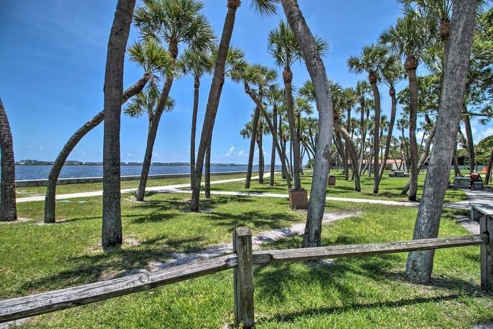A wooden fence borders a grassy park filled with palm trees overlooking a calm bay — 407 S Lakeside Drive, FL 33460, FL