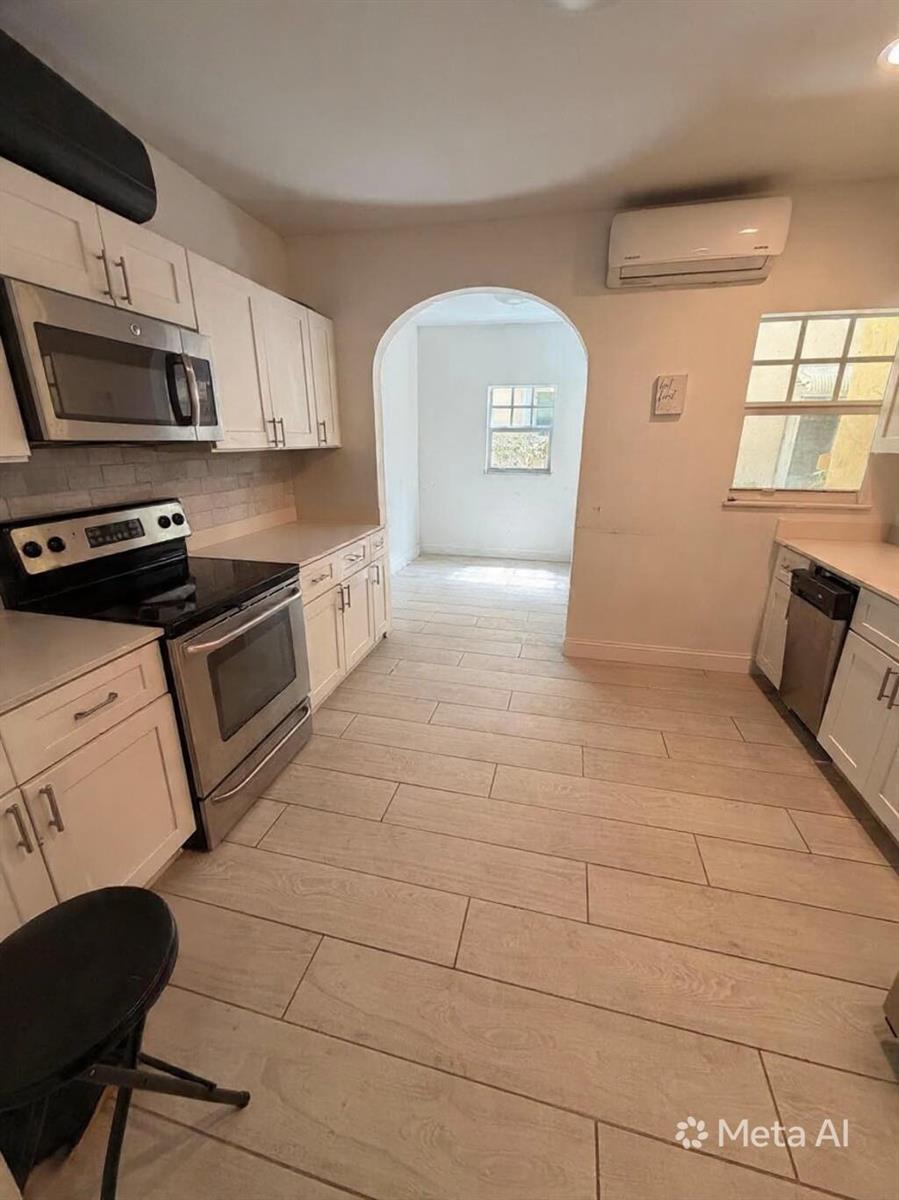 A kitchen with white cabinets, stainless steel appliances, and light wood-look tile flooring — 407 S Lakeside Drive, FL 33460, FL