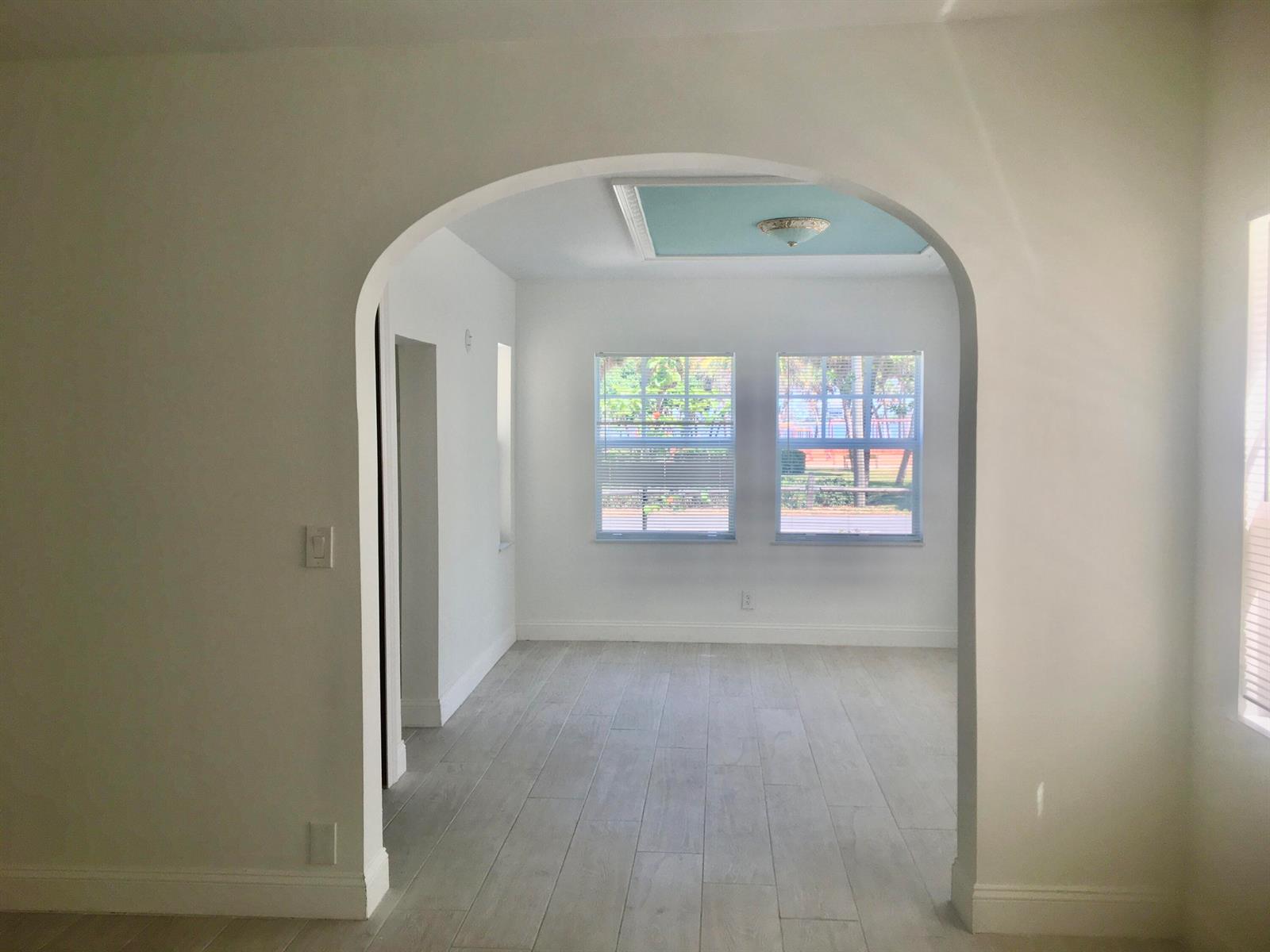 An arched doorway leads into a bright room with light wood-look flooring and two windows — 407 S Lakeside Drive, FL 33460, FL