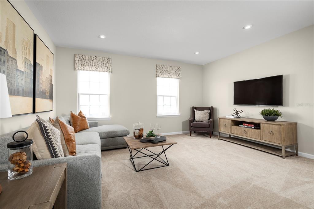 A living room features a grey sectional sofa, a wooden media console, and two windows — 9812 PINE MILL COURT, CLERMONT, FL