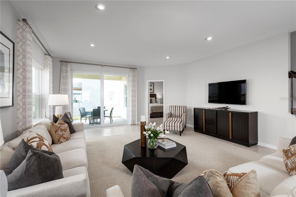 A living room features a beige sofa, a dark coffee table, and a wall-mounted television — 9812 PINE MILL COURT, CLERMONT, FL