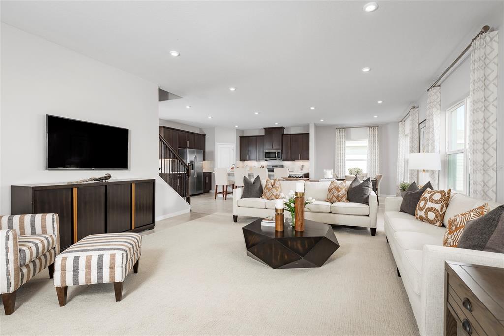 A living room with white sofas, a dark coffee table, and an open-concept kitchen — 9812 PINE MILL COURT, CLERMONT, FL