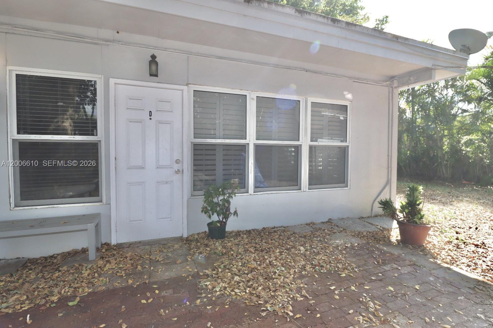 The exterior of a single-story unit features a white door, windows, and a brick patio — 2806 Taylor St # 0, Hollywood FL 33020, HOLLYWOOD, FL