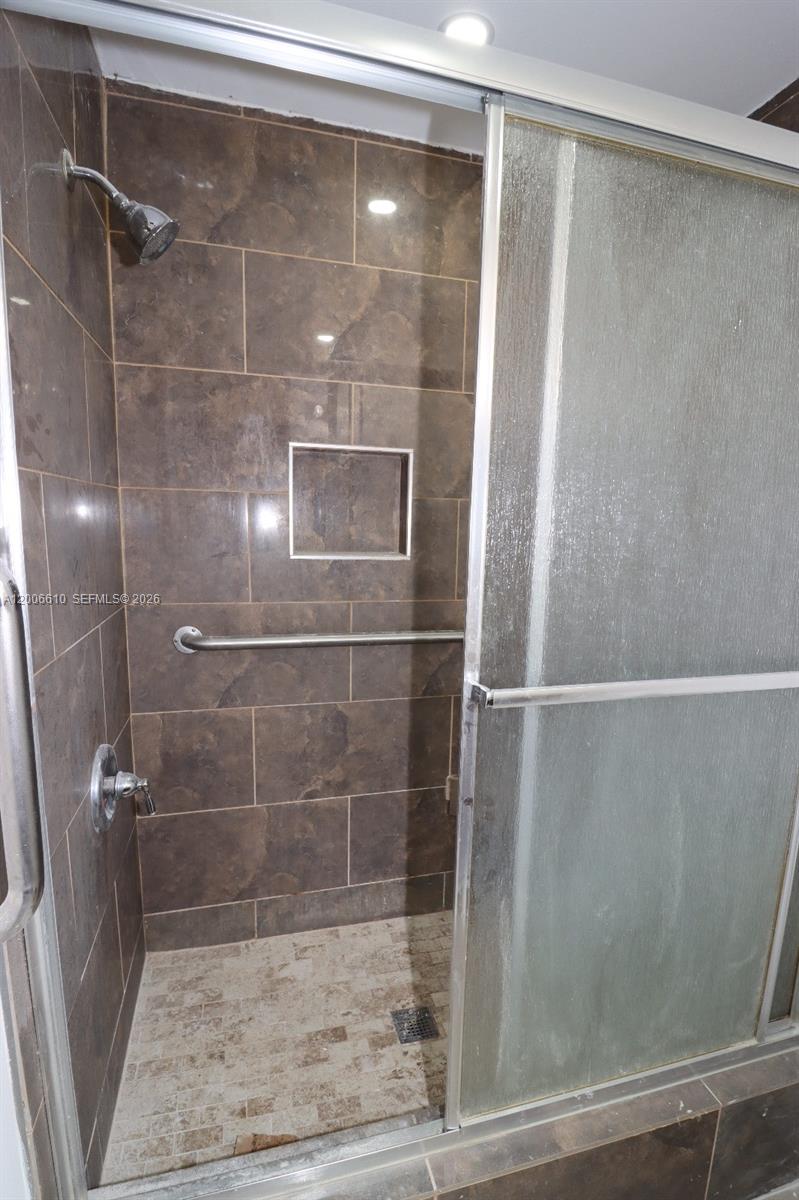 A walk-in shower features brown tiled walls, a built-in niche, and a metal grab bar — 2806 Taylor St # 0, Hollywood FL 33020, HOLLYWOOD, FL