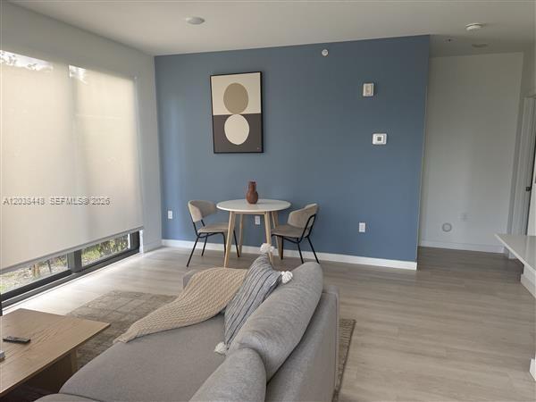 A living room features light wood flooring, a blue accent wall, and a dining area — 2201 Polk St # 101, Hollywood FL 33020, HOLLYWOOD, FL