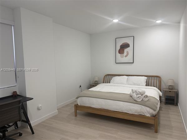 A bedroom features a wooden bed frame, light wood flooring, and a desk area — 2201 Polk St # 101, Hollywood FL 33020, HOLLYWOOD, FL