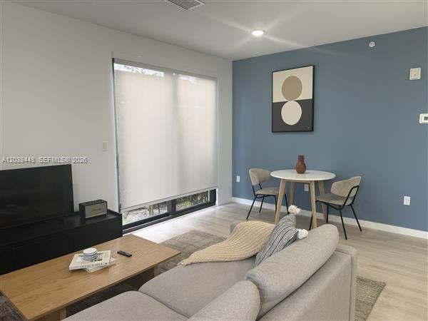 A living room features a grey sofa, a wooden coffee table, and a dining area — 2201 Polk St # 101, Hollywood FL 33020, HOLLYWOOD, FL