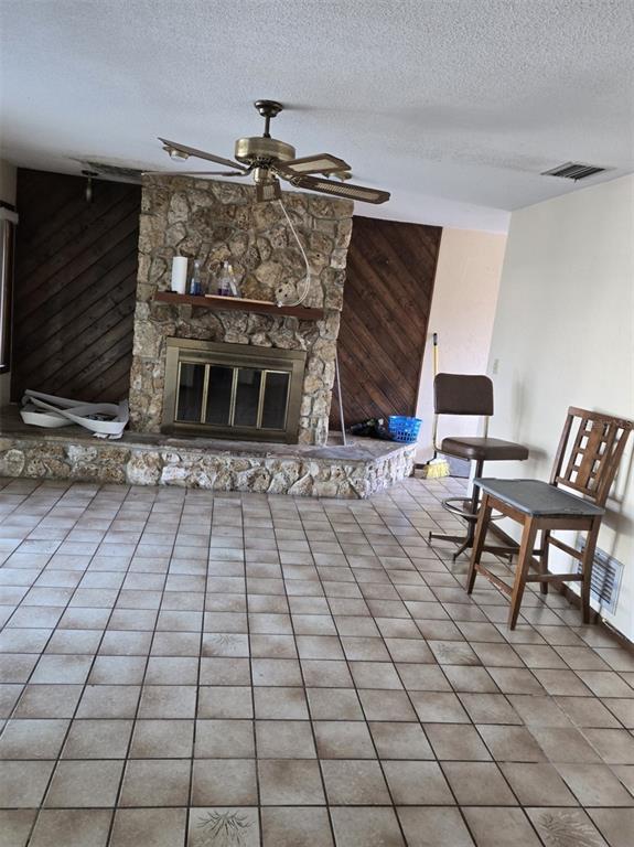 A room features a stone fireplace, diagonal wood paneling, a ceiling fan, and tiled flooring — 748 MERRIMAC DRIVE, PORT ORANGE, FL