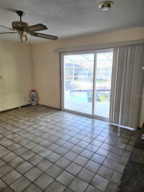 A room with tiled flooring, a ceiling fan, and sliding glass doors leading to a pool — 748 MERRIMAC DRIVE, PORT ORANGE, FL