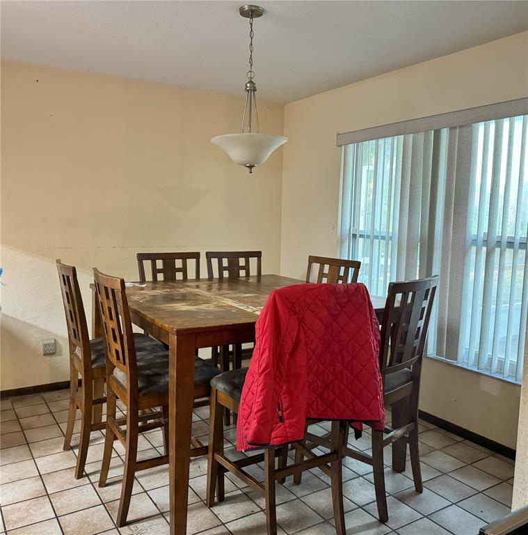 A dining room features a wooden table with six chairs, tile flooring, and a pendant light — 748 MERRIMAC DRIVE, PORT ORANGE, FL