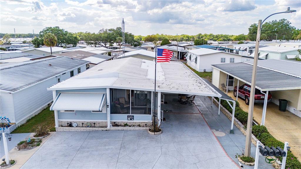 An elevated view of a light blue mobile home with a carport and American flag — 7135 EL DEWITT STREET, ZEPHYRHILLS, FL