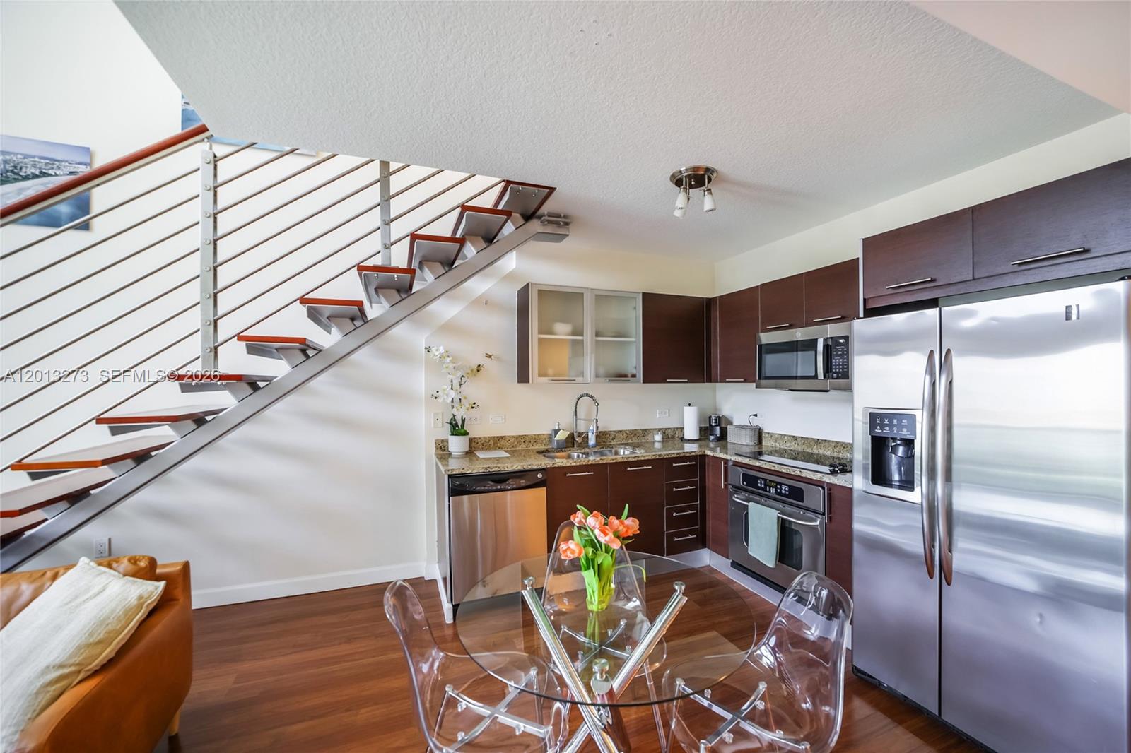 A kitchen with dark wood cabinets, stainless steel appliances, and an adjacent open staircase — 41 SE 5th St # 1003, Miami FL 33131, MIAMI, FL