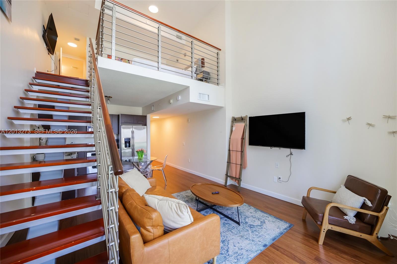 A living room features a staircase, a loft area, a leather sofa, and a television — 41 SE 5th St # 1003, Miami FL 33131, MIAMI, FL