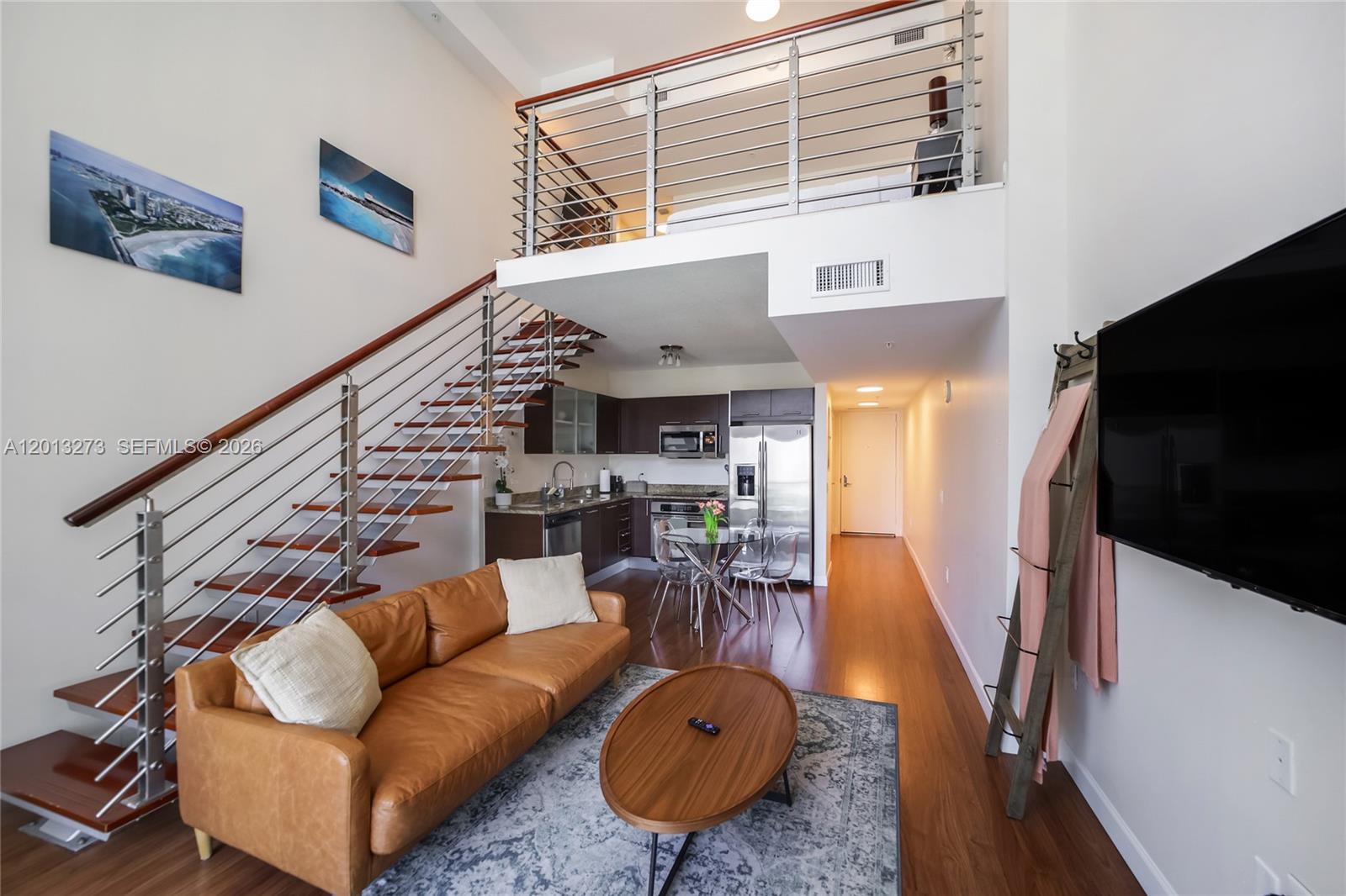 A modern loft apartment features a living area, kitchen, dining space, and an upper-level bedroom — 41 SE 5th St # 1003, Miami FL 33131, MIAMI, FL