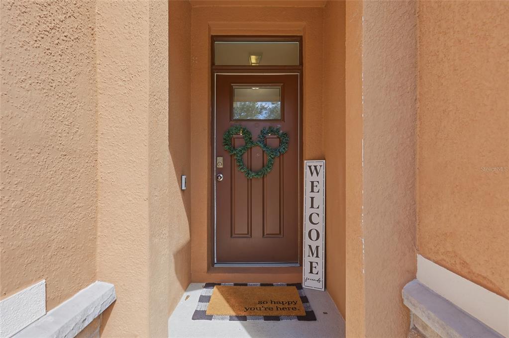 A brown front door with a Mickey Mouse wreath sits under a covered entryway — 4930 HAROLD STANLEY DRIVE, KISSIMMEE, FL