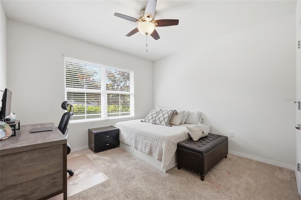 A bedroom with a desk, a bed with white bedding, and a ceiling fan — 4930 HAROLD STANLEY DRIVE, KISSIMMEE, FL