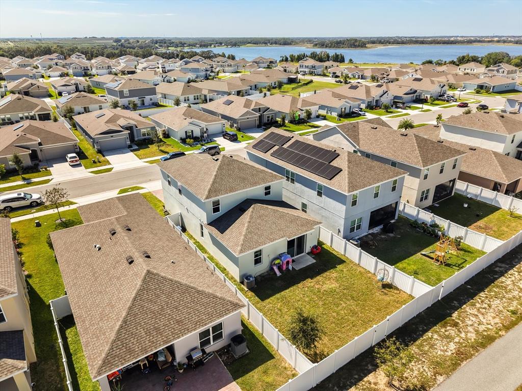 An aerial view shows a suburban neighborhood with houses, solar panels, and a nearby lake — 6940 CHURCH LAKE STREET, GROVELAND, FL