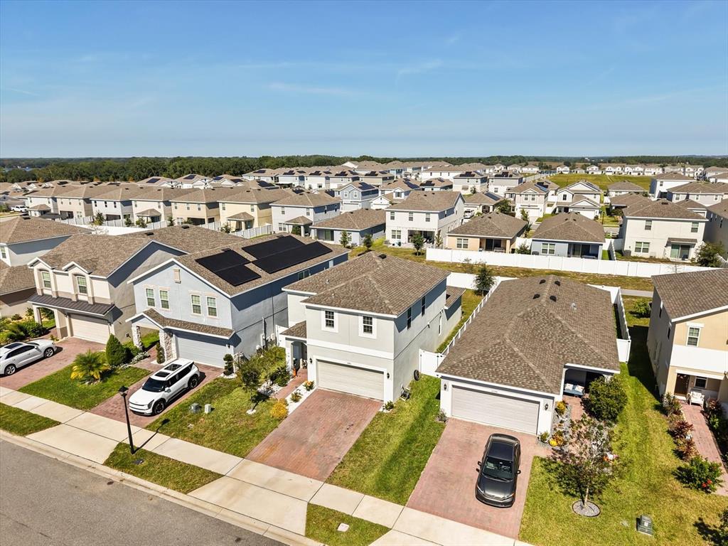 An aerial view shows several suburban houses with driveways, lawns, and solar panels on roofs — 6940 CHURCH LAKE STREET, GROVELAND, FL