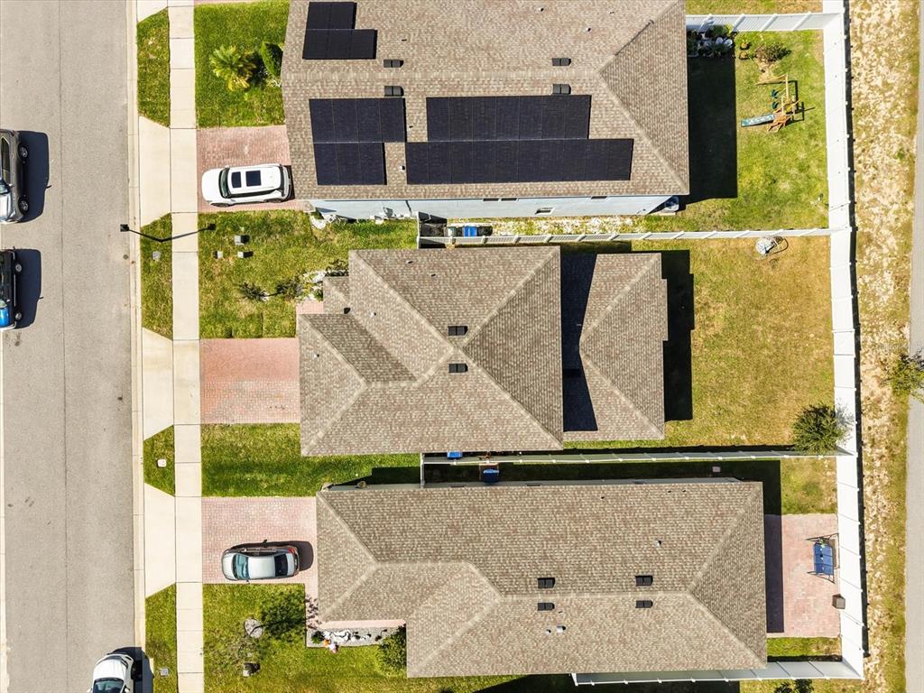An aerial view shows three suburban houses with driveways, lawns, and solar panels — 6940 CHURCH LAKE STREET, GROVELAND, FL