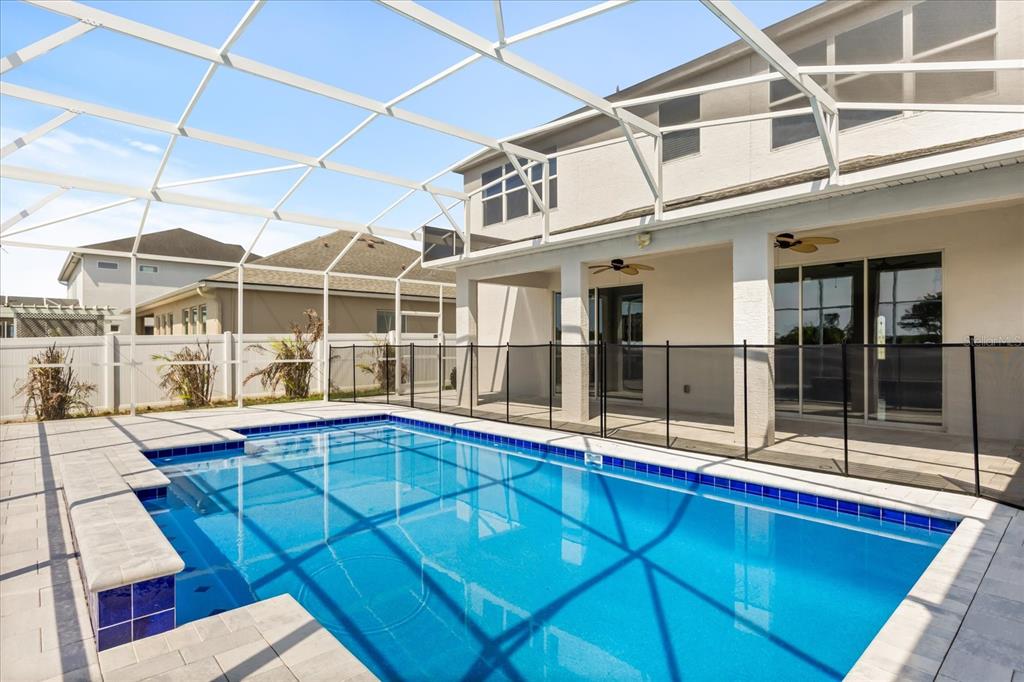 A backyard swimming pool with a screened enclosure and a black safety fence — 1926 MENDOCINO LANE, PORT ORANGE, FL